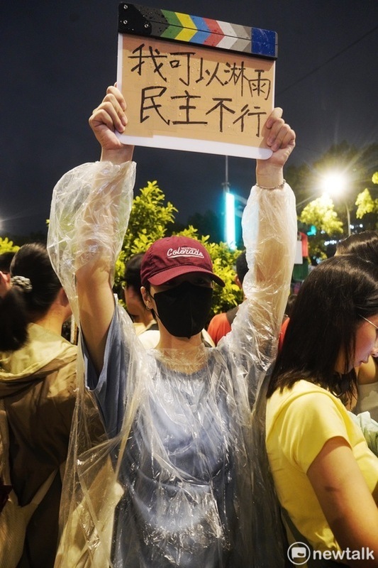游同學拿著「我可以淋雨，民主不行」的自製手牌站在大雨中和大家一起表達抗議國會惡法的心聲。   圖：張良一攝