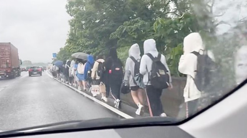 有民眾在國道三號直擊一群學生沿著路肩淋雨走路北上。   圖:翻攝自重機車友/各區路況天氣、資訊分享中心臉書