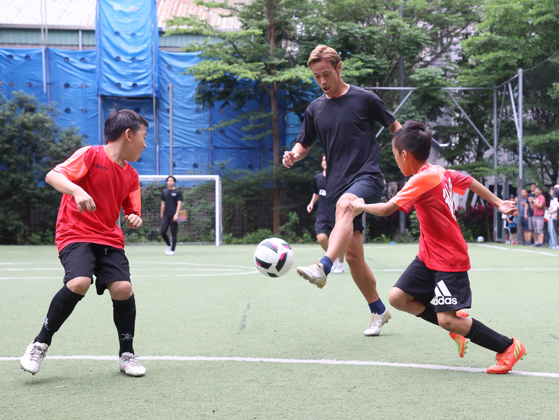 日本傳奇足球球星本田圭佑（前中）訪台，25日現身台北市萬華運動中心，推廣「4對4足球賽」，並親自下場踢球，與小球員們交流。   圖：中央社