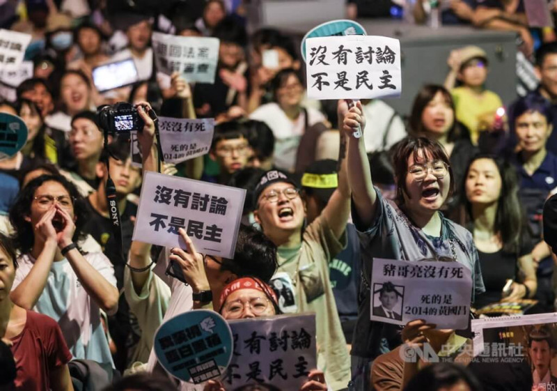 24日晚上立院周邊集結大批人潮，青島東路上民眾手持寫有「沒有討論 不是民主」的標語表達立場。   圖/中央社