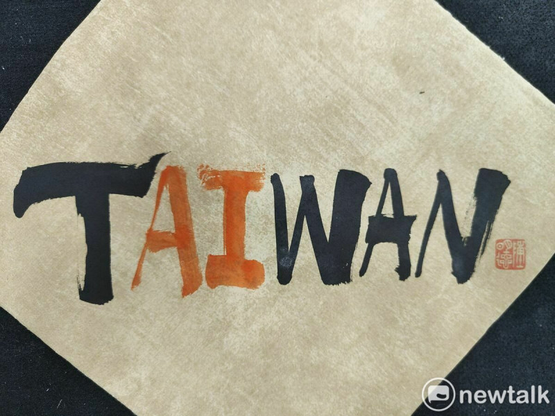 書法家陳明德發現台灣的英文TAIWAN似乎早已暗藏密碼，中間恰巧夾著「AI」兩字，遂用毛筆蘸墨援筆一揮，其中AI用朱液書寫，凸顯AI的視覺感與重要性，其創意和蒼勁筆力，見者無不驚嘆。   圖：黃博郎／攝