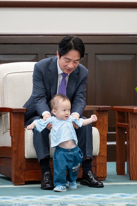 總統賴清德阿公上身，抱起許顥騰同學的小弟弟。   圖：總統府提供