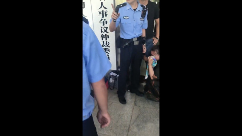 一名女子抱住自己老闆的大腿試圖討薪，當地警方卻向圍觀群眾威脅稱，誰敢幫她就會落得跟她一樣的下場。   圖：擷取自 @zhihui999 X 分享影片