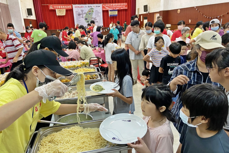 餐旅系學生為小朋友挾取美食，不忘詢問份量要多少。   圖：弘光科大/提供