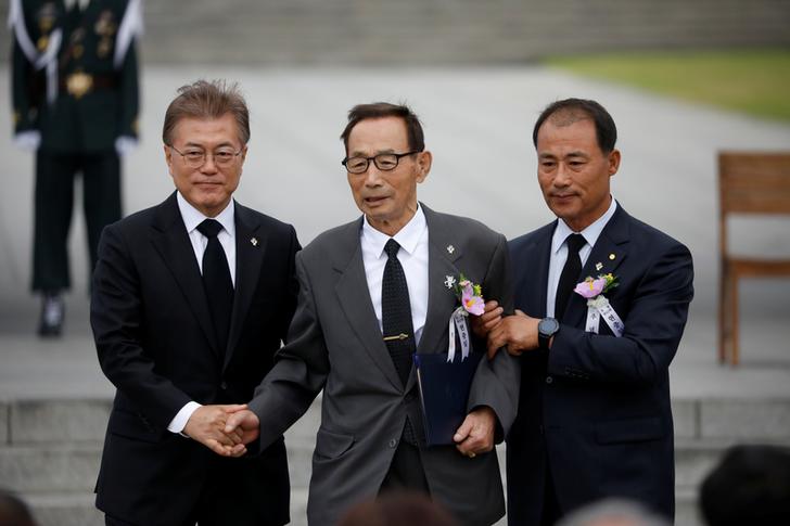 前南韓總統文在寅2017年6月出席韓戰陣亡軍人紀念日活動時，在國家公墓攙扶一名退伍老兵。   圖：達志影像／路透社（資料照）