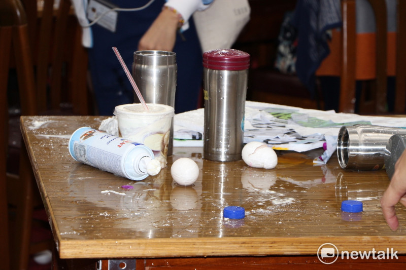 立院桌上擺了抗議用的雞蛋、鮮奶油，及潑完的水瓶。   圖：廖品瑄/攝