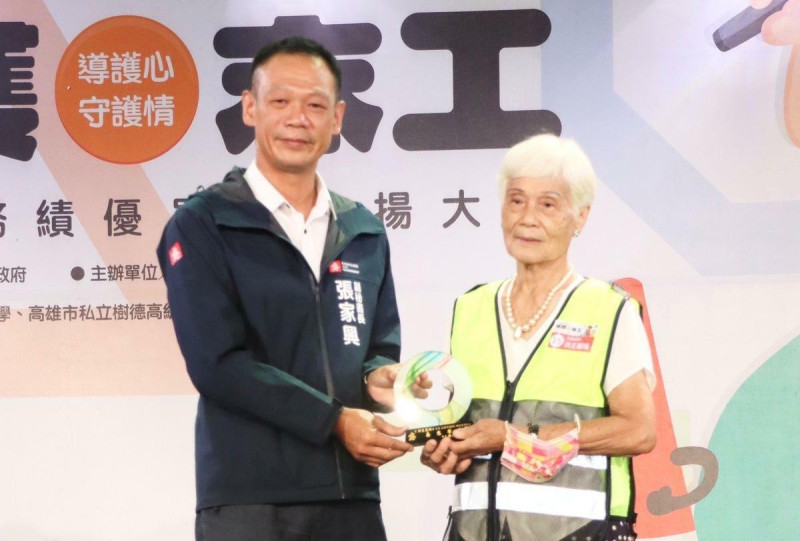 張家興頒獎表揚最年長的86歲志工代表洪王麗珠(右)。   圖：高雄市教育局/提供