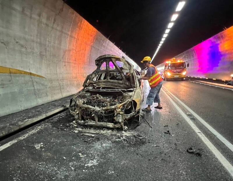 國道5號雪山隧道北向車道火燒車，消防人員滅火後，汽車殘留焦黑骨架。   圖：警方提供