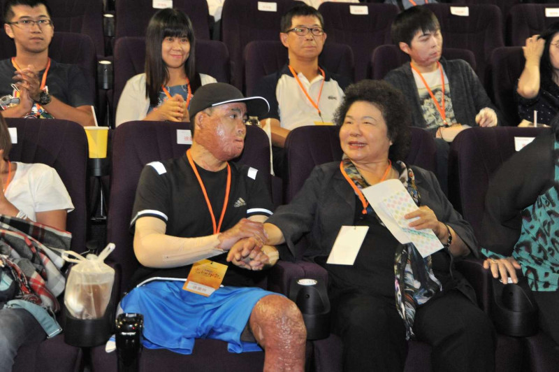 高雄市長陳菊在「光的印記」首映會中坐在高雄氣爆傷者的座位旁給他加油打氣。   圖 : 高雄市政府/提供