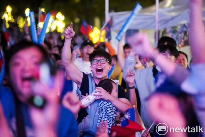 一位年輕的爸爸抱著孩子，激動的台灣隊亮麗的表現歡呼。   圖：張良一/攝