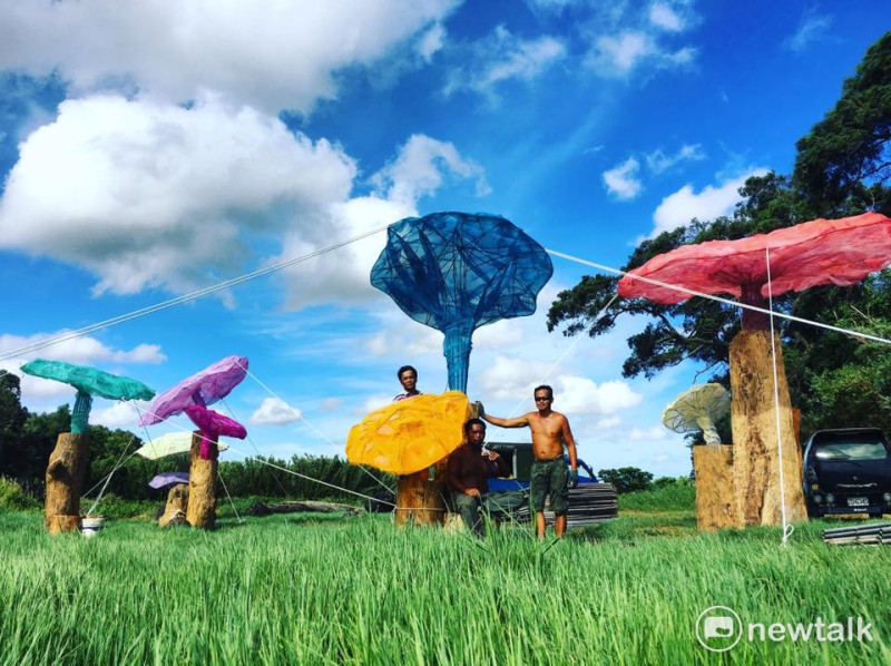 「2017桃園地景藝術節」主場地──觀音白千層林道旁，有藝術家蕭凱文以12根漂流木創作出一朵朵立於牧草田上的裝置藝術「補囊」，在藍天襯托下相當醒目。   圖：桃園市文化局提供