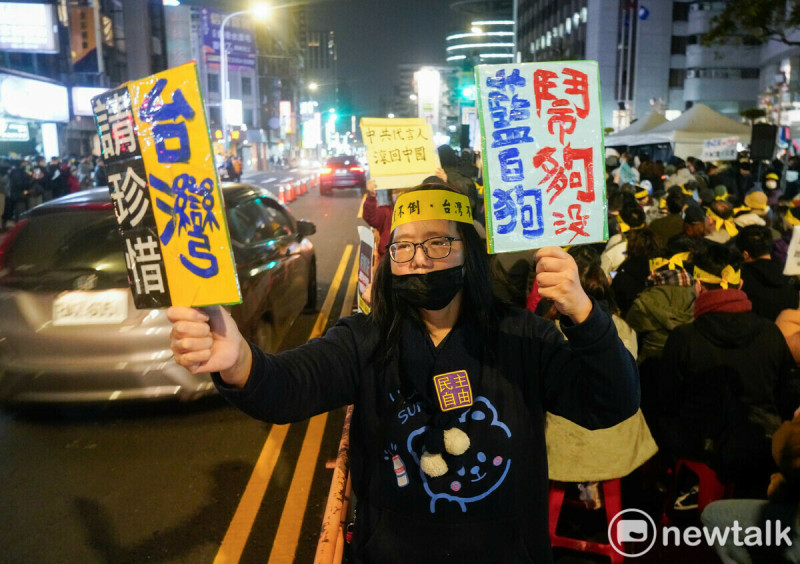 一位市民拿著『請珍惜台灣 藍白狗 鬧夠沒』手板，向經過的市民表達訴求。   圖：張良一/攝