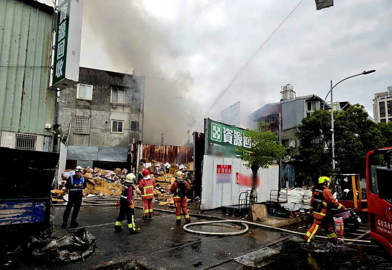 新北市三重區泉州街一處資源回收場10日下午發生火警，室外堆置物品起火燃燒，竄出陣陣白煙，消防獲報馳援，環保局則持續監控空氣品質變化。   圖：中央社/翻攝畫面