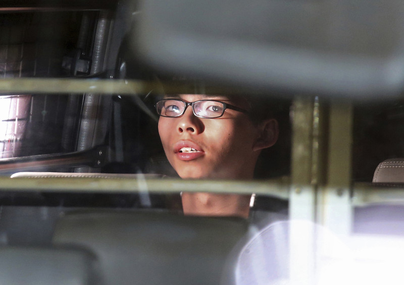 香港泛民主派政治新星黃之鋒17日遭判決入監，隨即坐上囚車離去，而雙學三子遭到政治迫害的疑雲日益擴大。   圖：達志影像/美聯社