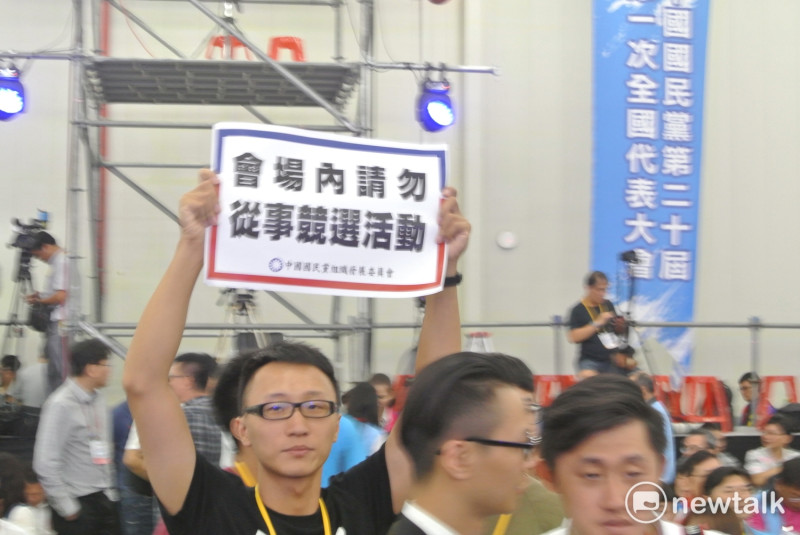 工作人員舉著「會場內請勿從事競選活動」牌子，表情無奈。   圖：唐復年/攝