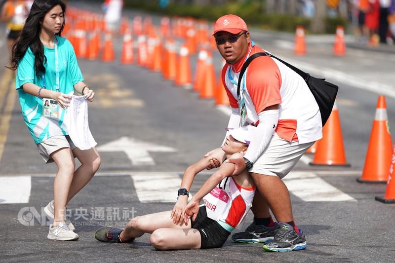 台北世大運27日在仁愛路進行女子半程馬拉松競賽，由 於天氣炎熱，一名土耳其選手（中）抵達終點後不支倒 地，工作人員上前攙扶。   圖 : 中央社