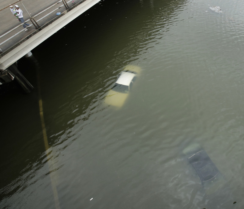 颶風哈維侵襲德州休士頓，一位民眾從高架橋上看淹沒在水裡的車輛。   圖 : 達志影像/美聯社