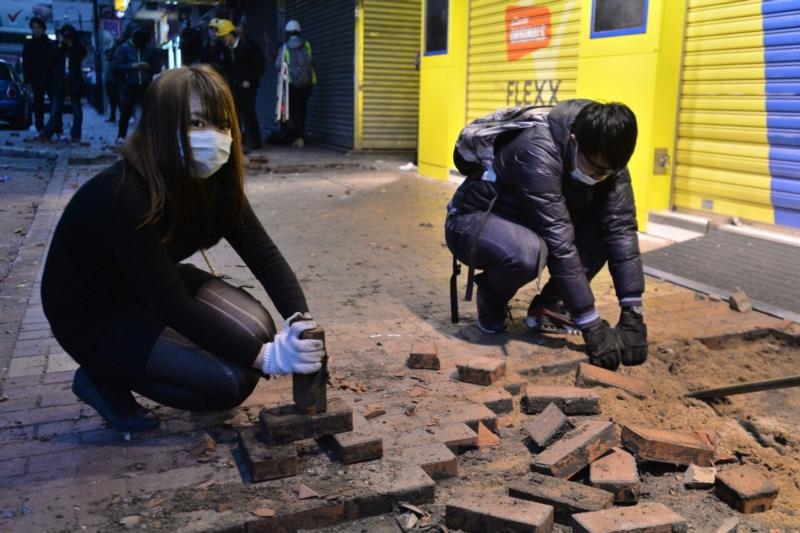 香港旺角騷動事件中，有37人被控「暴動罪」，當年17歲的李倩怡也是被告之一。圖為參與騷動者，在街上挖掘磚頭丟擲警方。   圖 : 翻攝自香港高登.com