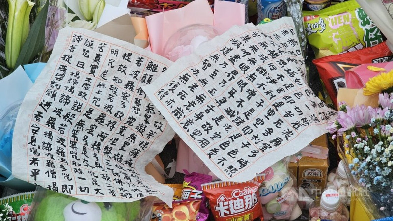 新北市三峽區19日發生重大車禍釀死傷,不少民眾在事發路口擺滿鮮花、零食飲料與玩偶,也有民眾到場放置抄寫的佛經表達哀思。中央社記者王鴻國攝 114年5月21日
