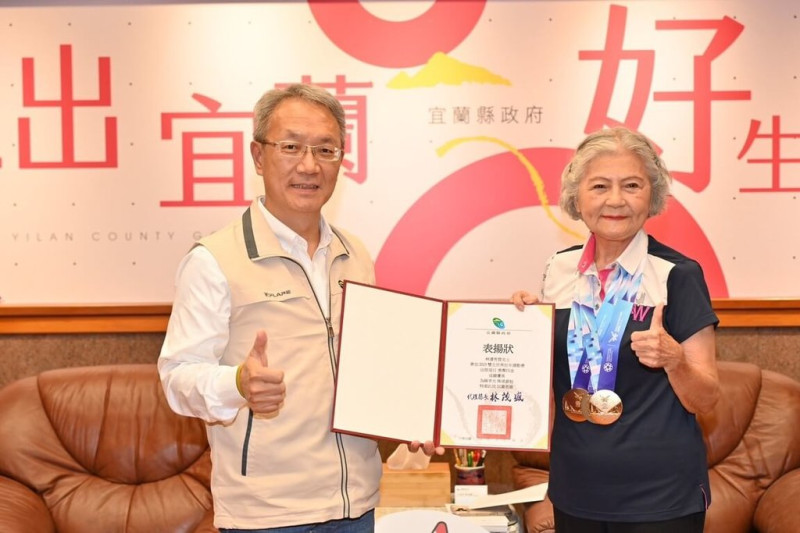 有「噴射機阿嬤」美譽的88歲林潘秀雲（右），曾因韌帶傷勢幾乎無法行走，她選擇靠運動復健，經歷3年努力重返跑道，在2025雙北世壯運拿下4面金牌，宜蘭縣代理縣長林茂盛（左）26日接見表揚。（宜蘭縣政府提供）中央社記者王朝鈺傳真  114年5月26日   