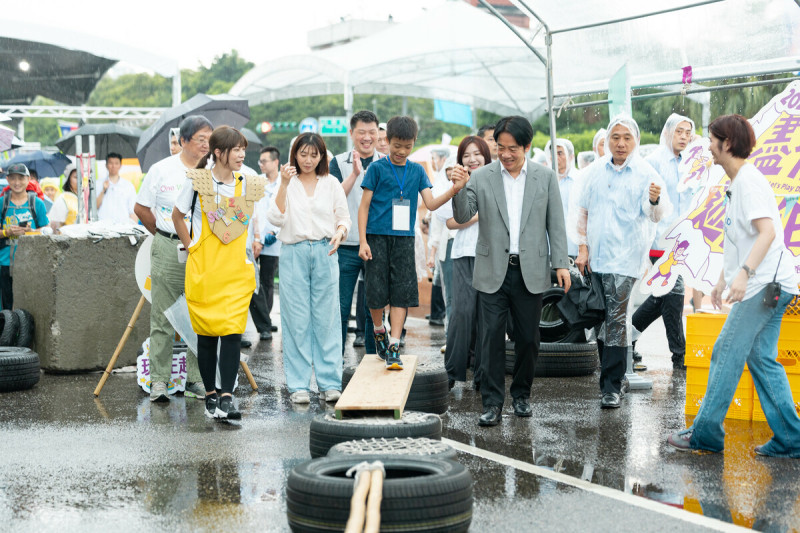 賴清德在雨中與孩童一起遊戲。   圖：總統府提供