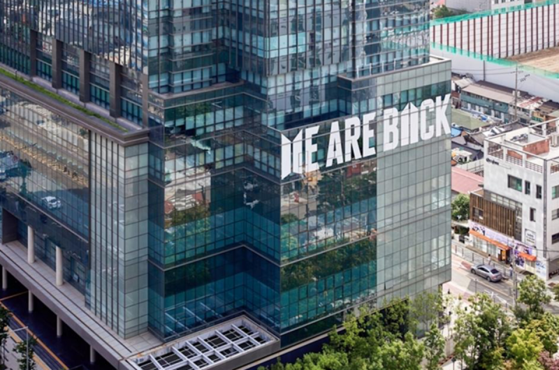 BTS所屬的經紀公司HYBE娛樂總部大樓外牆,已張貼著「WE ARE BACK」標語。 圖:翻攝自BIGHIT MUSIC官網