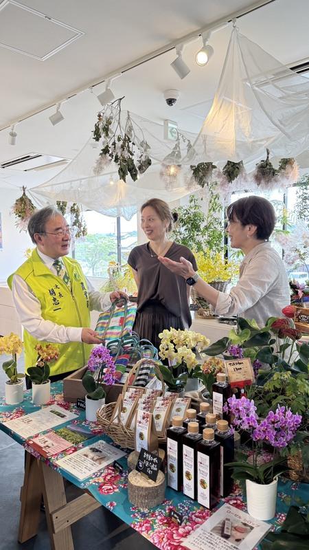 胡忠一副部長赴日推廣花祭，現場賣花也賣香腸，結合五感體驗打造台味市集，吸引日本民眾關注。   圖：農業部／ 提供