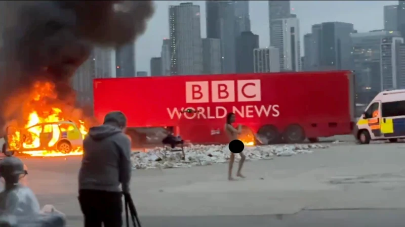 Jhaj 曾拍攝影片,在一台假《BBC News》新聞車前裸體,還焚燒了車子。 圖:翻攝自 X Jhaj 曾拍攝影片,在一台假《BBC News》新聞車前裸體,還焚燒了車子。 圖:翻攝自 X