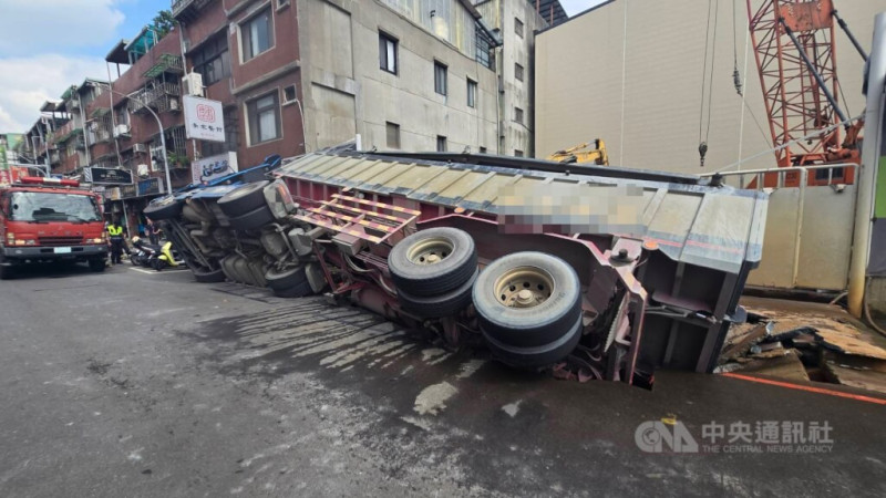 新北市三重區龍門路一處工地前路面26日塌陷，造成一輛停放路旁的砂石車側翻，消防獲報前往救援，幸無人受傷。（翻攝畫面）中央社記者趙敏雅傳真  114年6月26日   