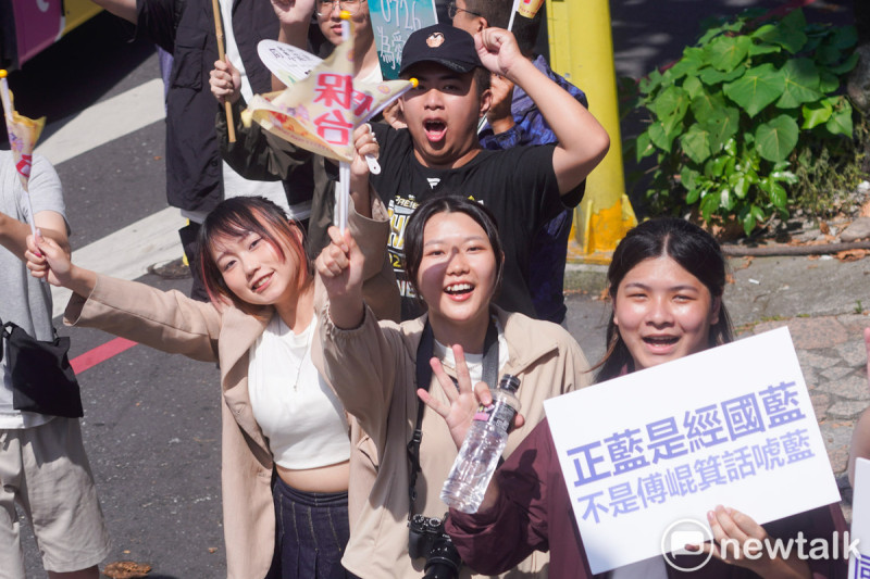 護國大遶境首日從花蓮出發,花蓮市民高舉著「正藍是經國藍不是傅崐萁的話唬藍」手舉牌,站在路口歡迎護國大遶境的香燈腳。 圖:張良一/攝