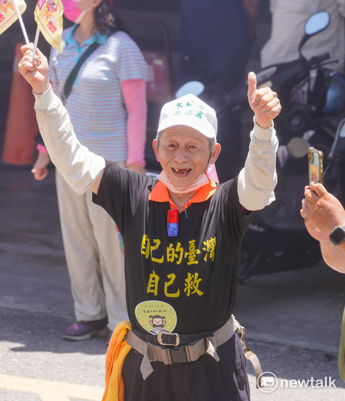 護國大遶境首日從花蓮出發,一位花蓮市民身穿「自己的台灣自己救」黑T,站在路口歡迎護國大遶境的香燈腳。 圖:張良一/攝
