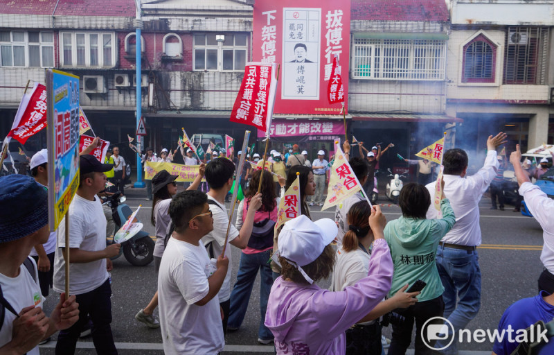 參與護國大遶境的罷團志工向站在路口的花蓮市民揮手致意。在市民背後有一幅「拔傅行動 下架傅崐萁」的廣告看板懸掛在外牆。 圖:張良一/攝