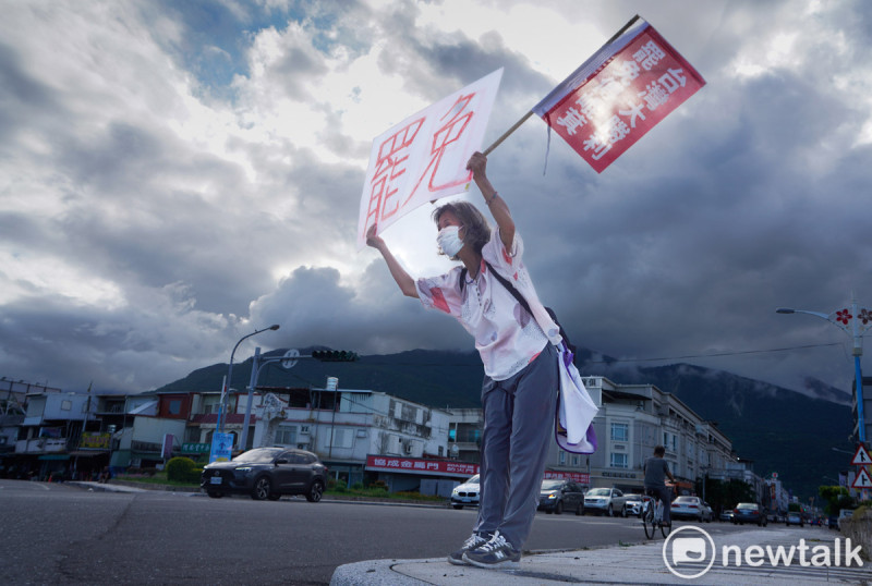 一位花蓮市民高舉「同意罷免」手舉牌,並彎腰向市民拜票。 圖:張良一/攝