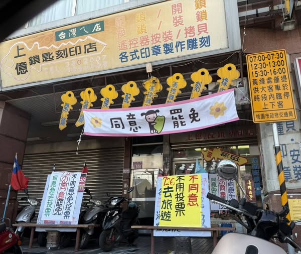 國民黨桃園市議員詹江村PO出照片，指八德區一家刻印店門口標語涉嫌違反《公職人員選舉罷免法》第104條第1項第1款，直嗆「老闆你被告了」。   圖：翻攝「臉書」詹江村粉絲專頁