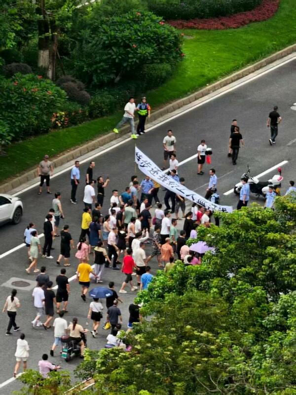 7 月 22 日,福建泉州特步鞋廠門口上演罕見場景:工人舉著橫幅走上主幹道,高呼「討薪」口號,甚至有工人直接橫躺在路中,封鎖三條車道。現場緊張,多名荷槍實彈的警察迅速出動維穩。 圖:翻攝自X帳號@whyyoutouzhele