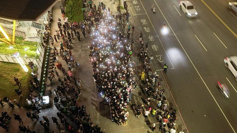 志工與市民以手機燈光排列出「點亮台灣」畫面，象徵人民以和平、溫柔但堅定的方式，照亮台灣的未來。   圖：Wecare高雄/提供