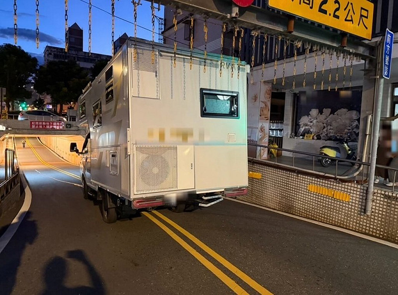 邱姓男子17日駕駛露營車行經宜蘭縣羅東鎮南昌東街地下道時，未注意限高2.2公尺標誌，車頂擦撞到限高門架，使得道路無法通行，公所派員以砂輪機切割懸掛在門架的鐵鍊，邱男才得以倒車脫困。（讀者提供）中央社記者王朝鈺傳真　114年8月18日   