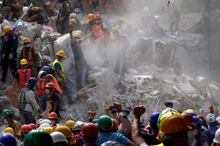 7.1級強震重創墨西哥首都墨西哥市，到處斷垣殘壁。一名搜救人員在瓦礫堆中發現生還者，趕緊以手勢示意現場保持安靜。目前已有4名台僑不幸罹難，1人失蹤等待救援。   圖：達志影像／路透社
