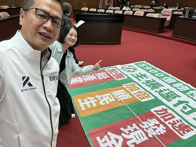 民進黨團幹事長吳思瑤找國民黨立委羅智強，一同在民進黨呼籲加速普發現金的布條前合照。   圖：擷取自羅智強臉書