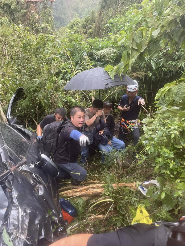 南投縣信義鄉台21線123公里處附近23日發生汽車墜谷意外，車輛被樹木擋住，卡在至少200公尺深處，車內4人受困。消防人車到場救出受困者，4人皆意識清醒、送醫治療。（南投縣消防局提供）中央社記者蕭博陽南投縣傳真  114年8月23日   