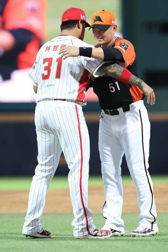 中華職棒味全龍隊27日晚間在天母球場交手統一獅隊,龍隊林智勝(左)賽前代表送上禮物給即將舉辦引退賽的獅隊老將胡金龍(右),兩人相擁致意。中央社記者趙世勳攝 114年8月27日
