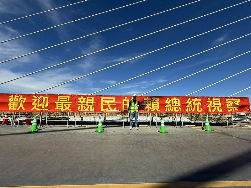 淡江大橋的全橋合龍典禮一度出現廠商掛上的「歡迎最親民的賴總統視察」字樣布條。   圖：陳偉杰/提供