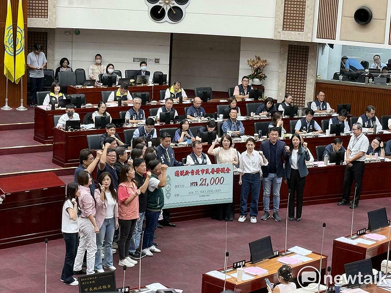 民進黨台北市議會黨團致贈上方寫著「2.1萬元」的大型支票給市長蔣萬安，呼籲還稅於民、普發現金。   圖：周煊惠 / 攝