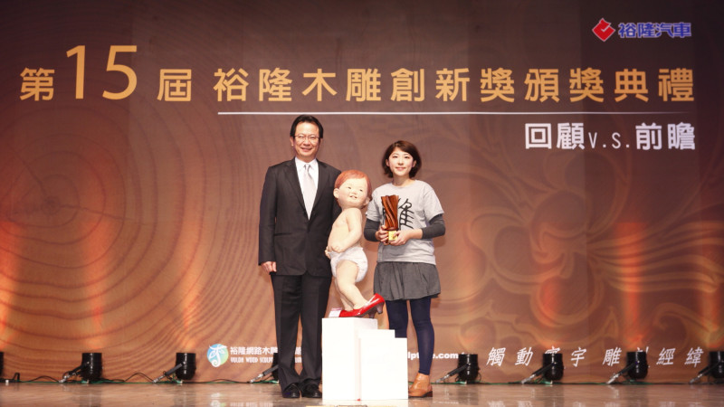 「第15屆裕隆木雕創新獎」公佈，年僅24歲的黃品彤（右）奪得首獎金質獎，從裕隆汽車總經理陳國榮(左)手中接過這份榮耀。。圖片來源：裕隆汽車提供。   
