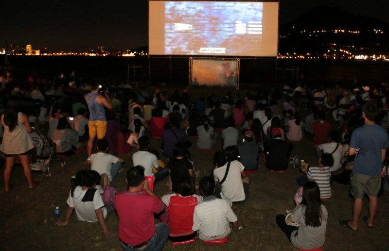 新北市政府新聞局19日晚上在淡水的金色水岸廣場放映紀錄片《一首搖滾上月球》，許多民眾扶老攜幼在夏日夜晚一起觀賞。圖：陳冠廷/攝。   