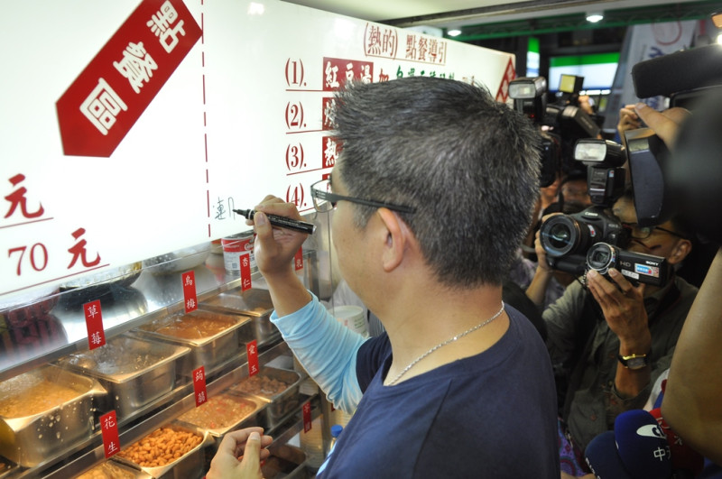 國民黨台北市長候選人連勝文今(25)日晚間2度到忠孝東路東區掃街拜票，並在知名甜點店的招牌上簽名。圖：劉奕霆/攝。   