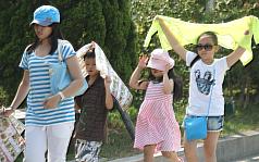台北市8日中午出現攝氏39.3度高溫，在戶外活動的小朋友難耐曝曬，利用帽子、外套、廣告紙等物品遮擋豔陽。圖：中央社。   