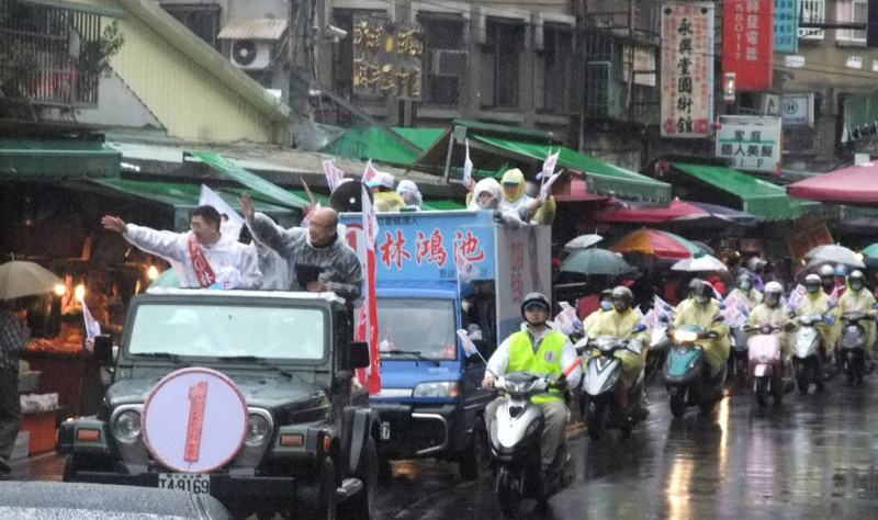 國民黨榮譽黨主席吳伯雄穿上雨衣的陪同新北市第6選區立委候選人林鴻池，展開一整天的車隊掃街拜票行程。圖片：陳冠廷/攝   