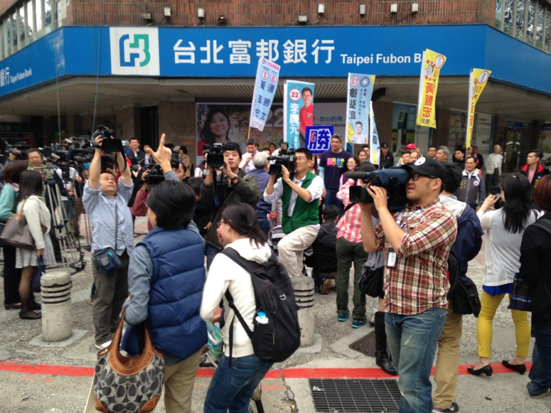 國民黨台北市長候選人連勝文今日上午到和平東路和復興南路口在街頭定點拜票，不過有民眾過馬路時，高舉「七」的手勢，連勝文則在一旁和民眾合照，並未注意到該民眾。圖：劉奕霆/攝。   