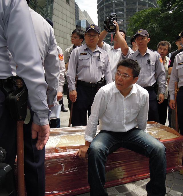 新北市議員陳明義索性坐在棺木上等待市府高層的回應。（記者陳冠廷攝）   